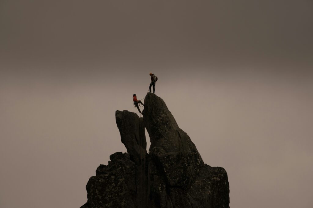 Achieving professional success through strong workplace resilience, depicted by mountain climbers.